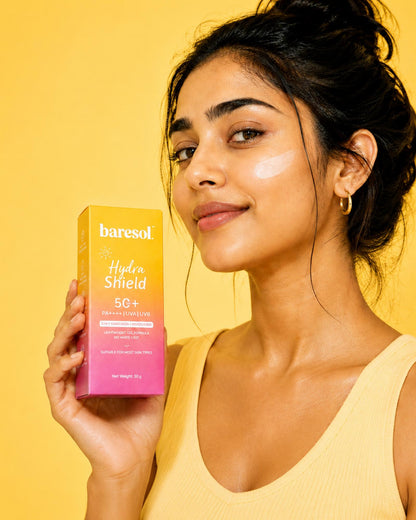 Woman holding a Baresol sunscreen box against a yellow background